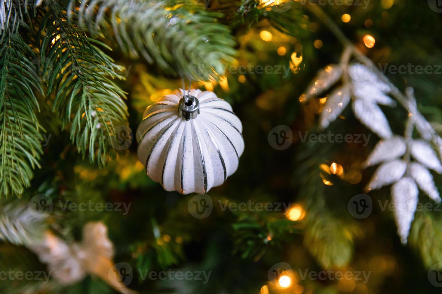 Classic Christmas decorated New year tree. Christmas tree with wite and silver decorations, ornaments toy and ball. Modern classical style interior design apartment. Christmas eve at home. photo