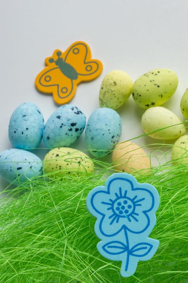 Artificial grass with colored eggs and blue flower background photo