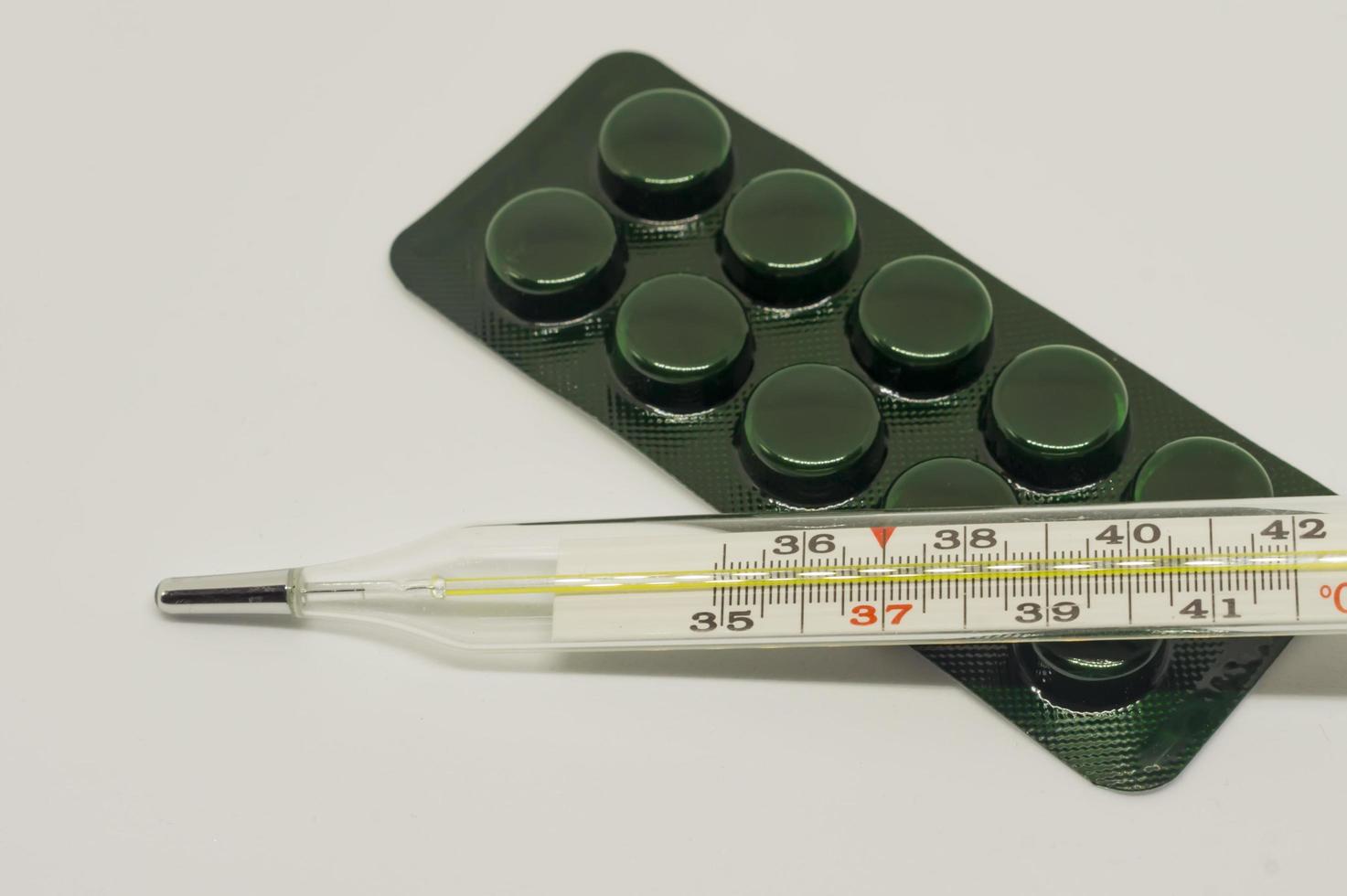 píldoras de medicina y termómetro sobre fondo blanco foto
