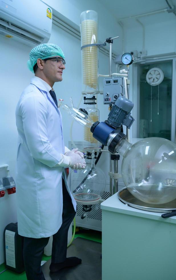 Scientists and assistants are in the machine room extracting oil and cannabis seeds. Inspecting cannabis oil extractor before starting to extract the prepared cannabis photo