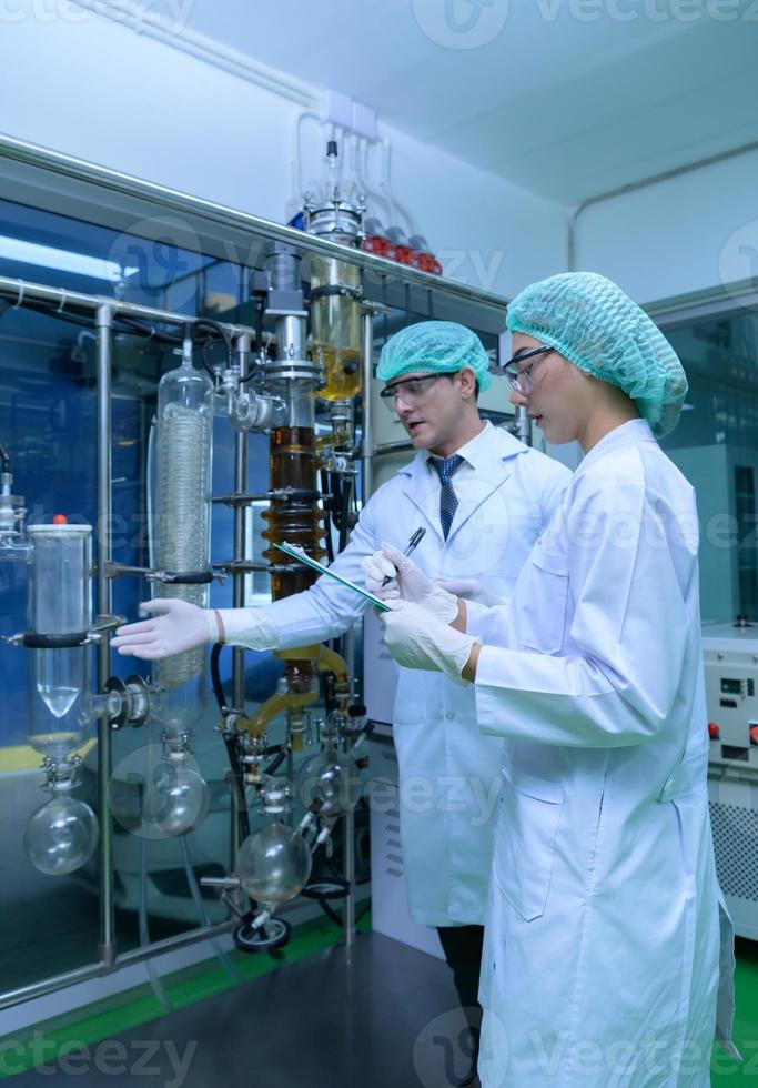 Scientists and assistants are in the machine room extracting oil and cannabis seeds. Inspecting cannabis oil extractor before starting to extract the prepared cannabis photo