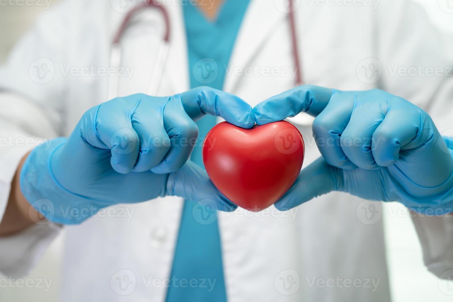 Doctor holding a red heart in hospital ward, healthy strong medical concept. photo