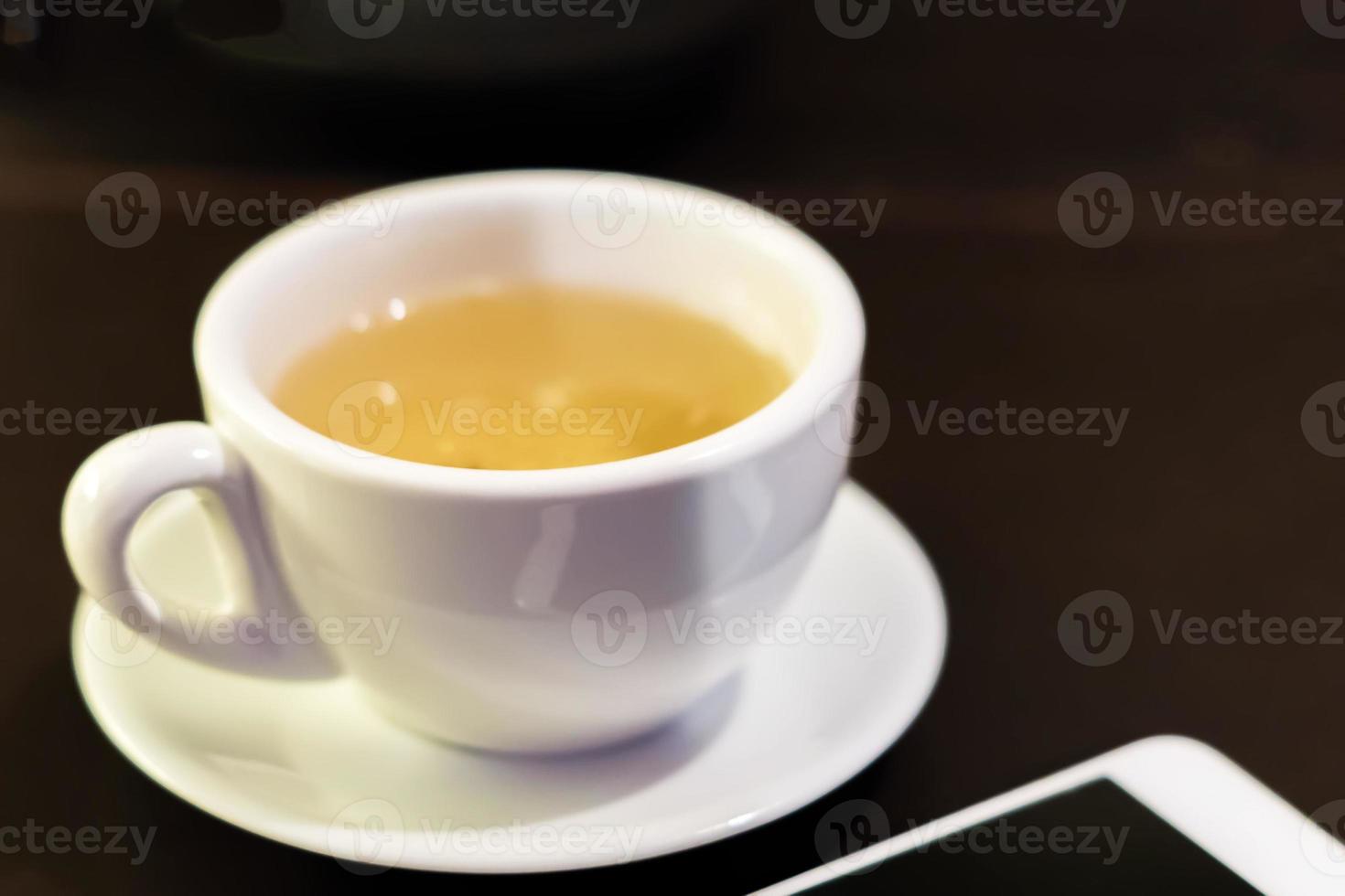 cup of green tea nd white phone on table photo