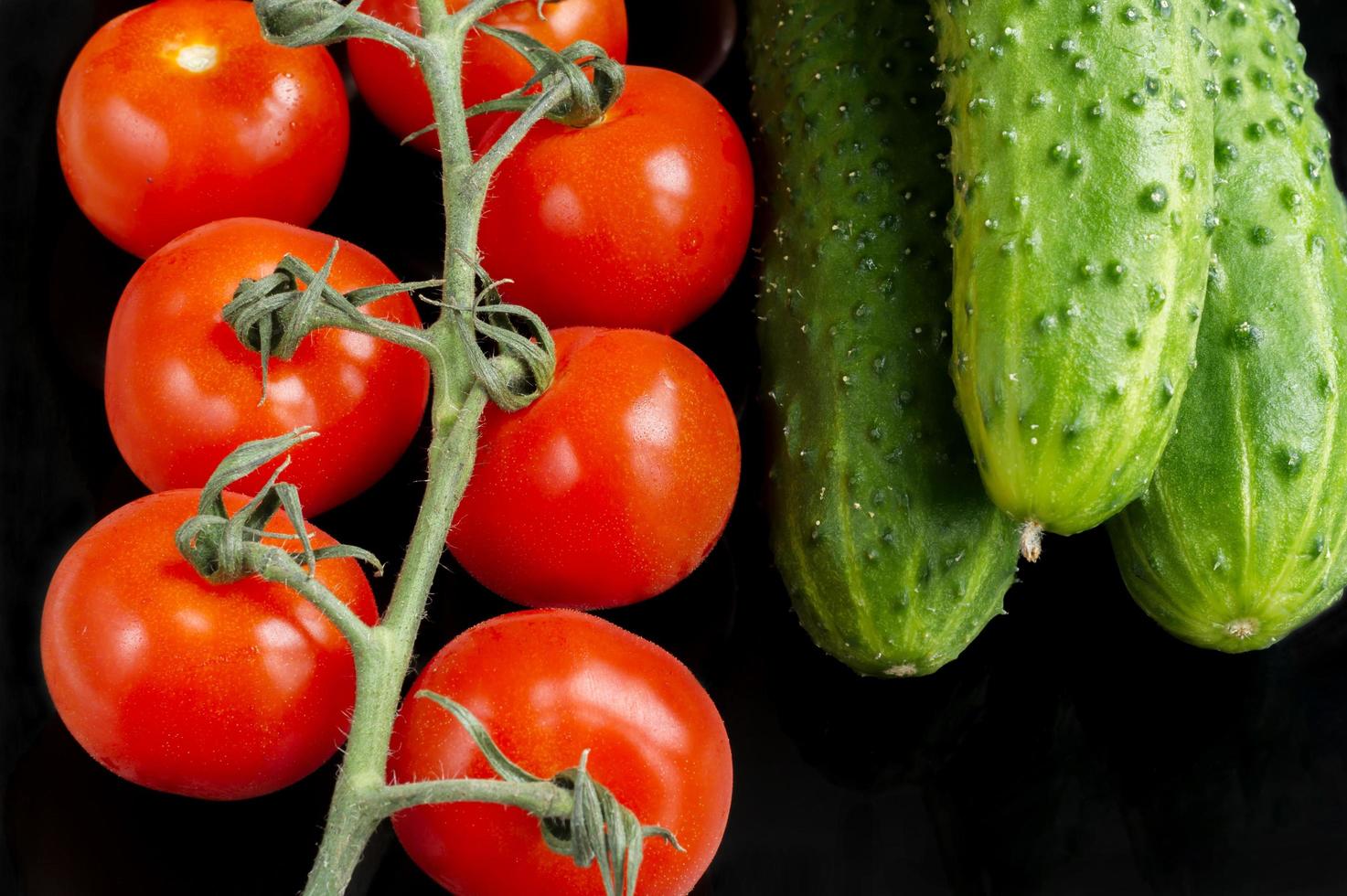 red toatoes and green cucumbers on black background photo