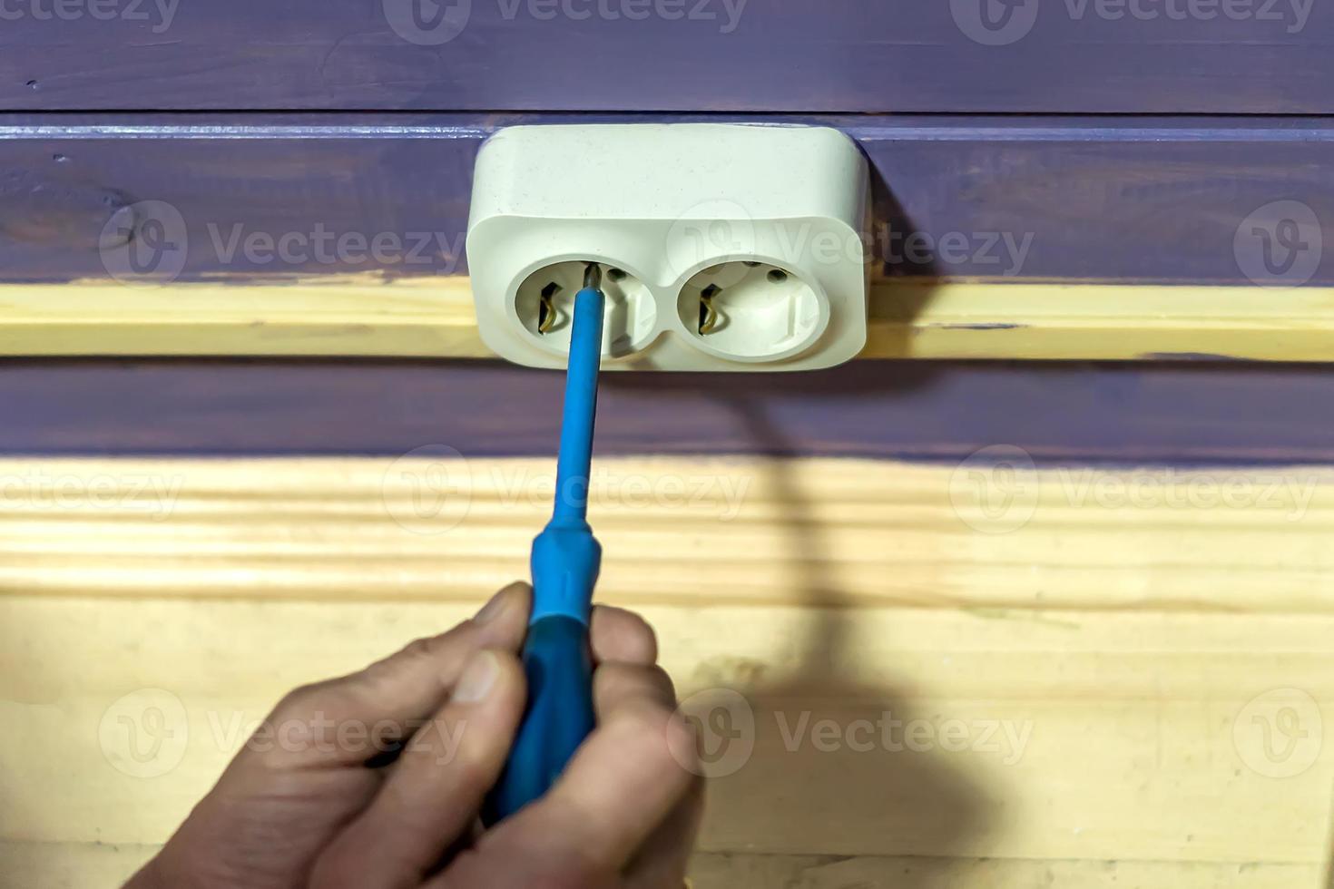 Closeup of man's hand installing socket on wooden wall at country house photo