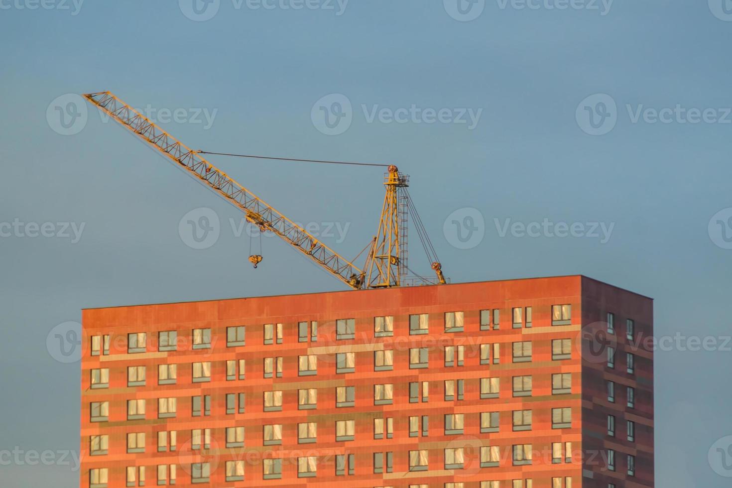 lift crane over building in sunset against blue sky photo