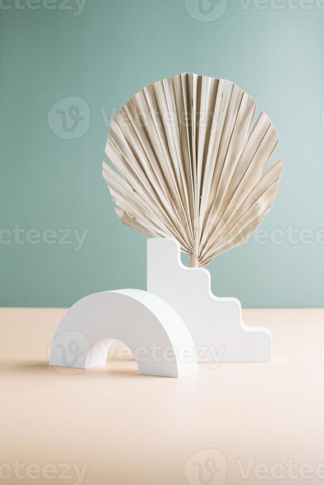 Podium for cosmetic product presentation. Abstract minimal geometrical form. Ladder podium with dry palm tree leaf, soft shadow. Scene to show products. Showcase, display case. photo