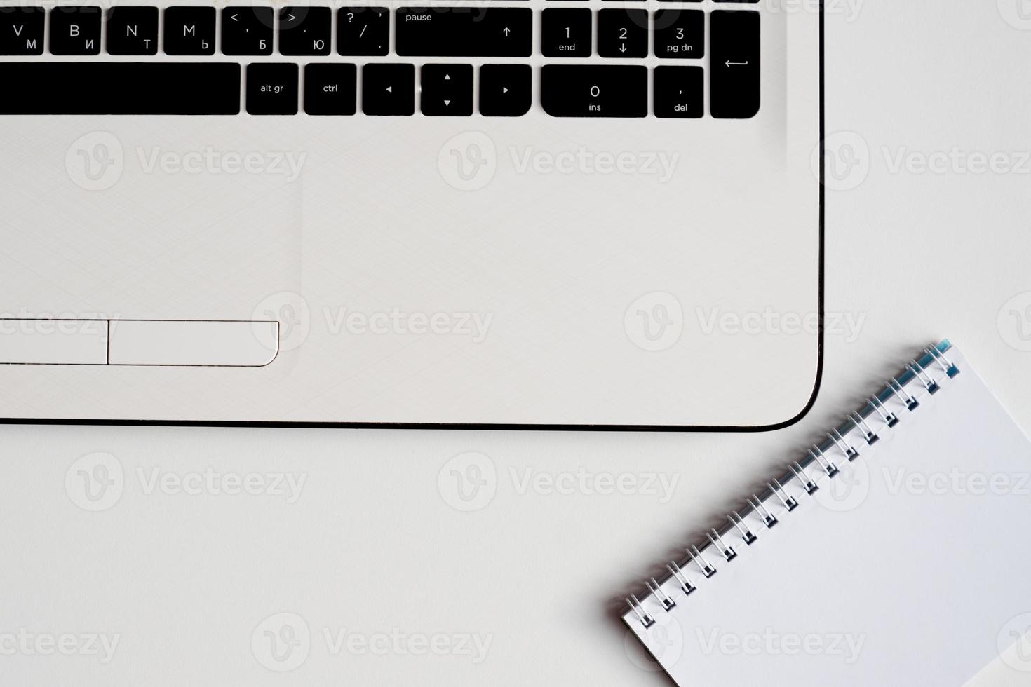 Closeup of white office desk with laptop and note book . Top view with copy space. photo