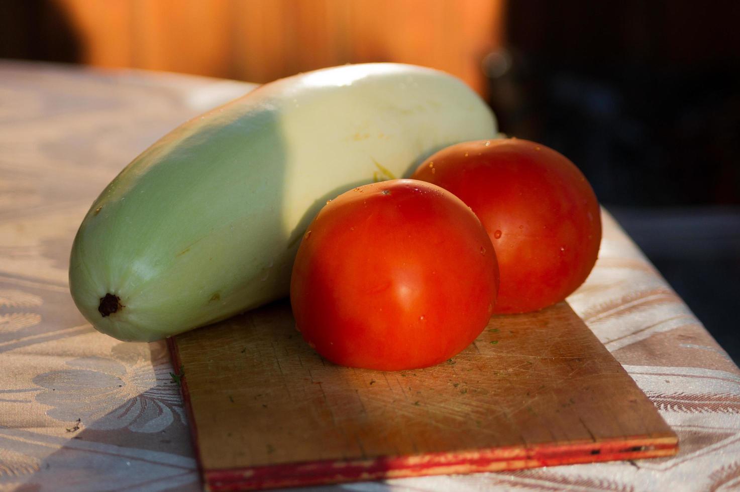 calabacines y tomates en una tabla para cortar foto