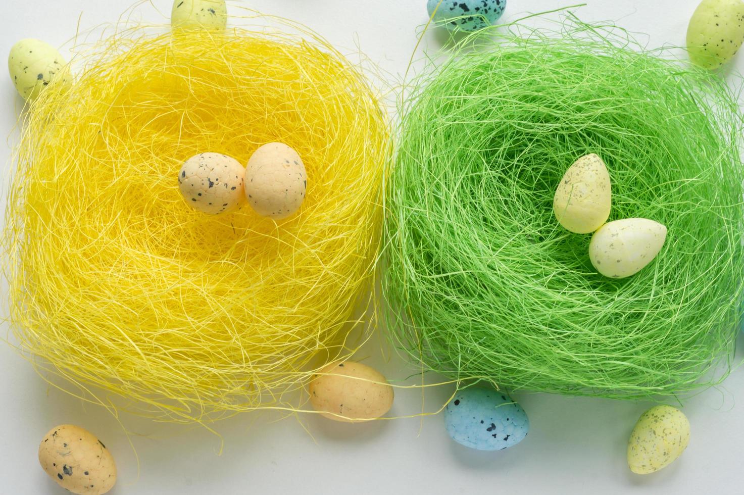 Artificial green and yellow nests with two eggs on white background photo