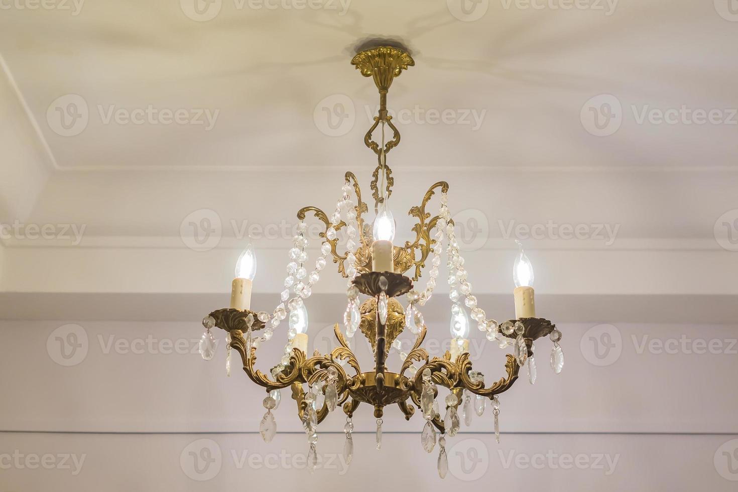 vintage chandelier hanging under white ceiling with stucco moldings photo