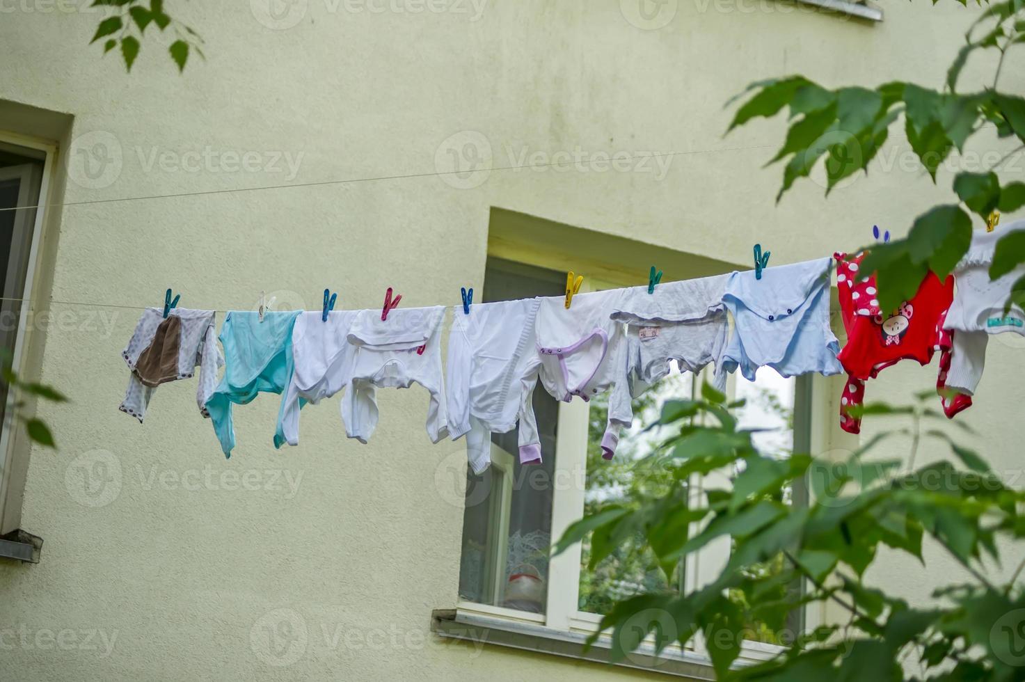 Baby clothes hanging on rope on the street photo