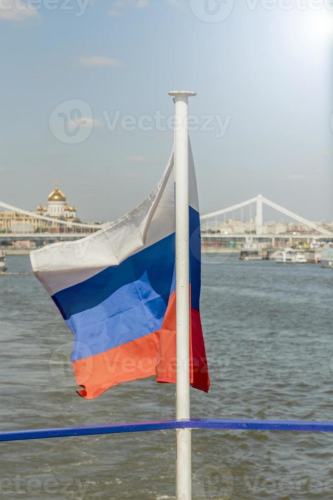 The National flag of Russia flay over the boat on Moscow city background. photo