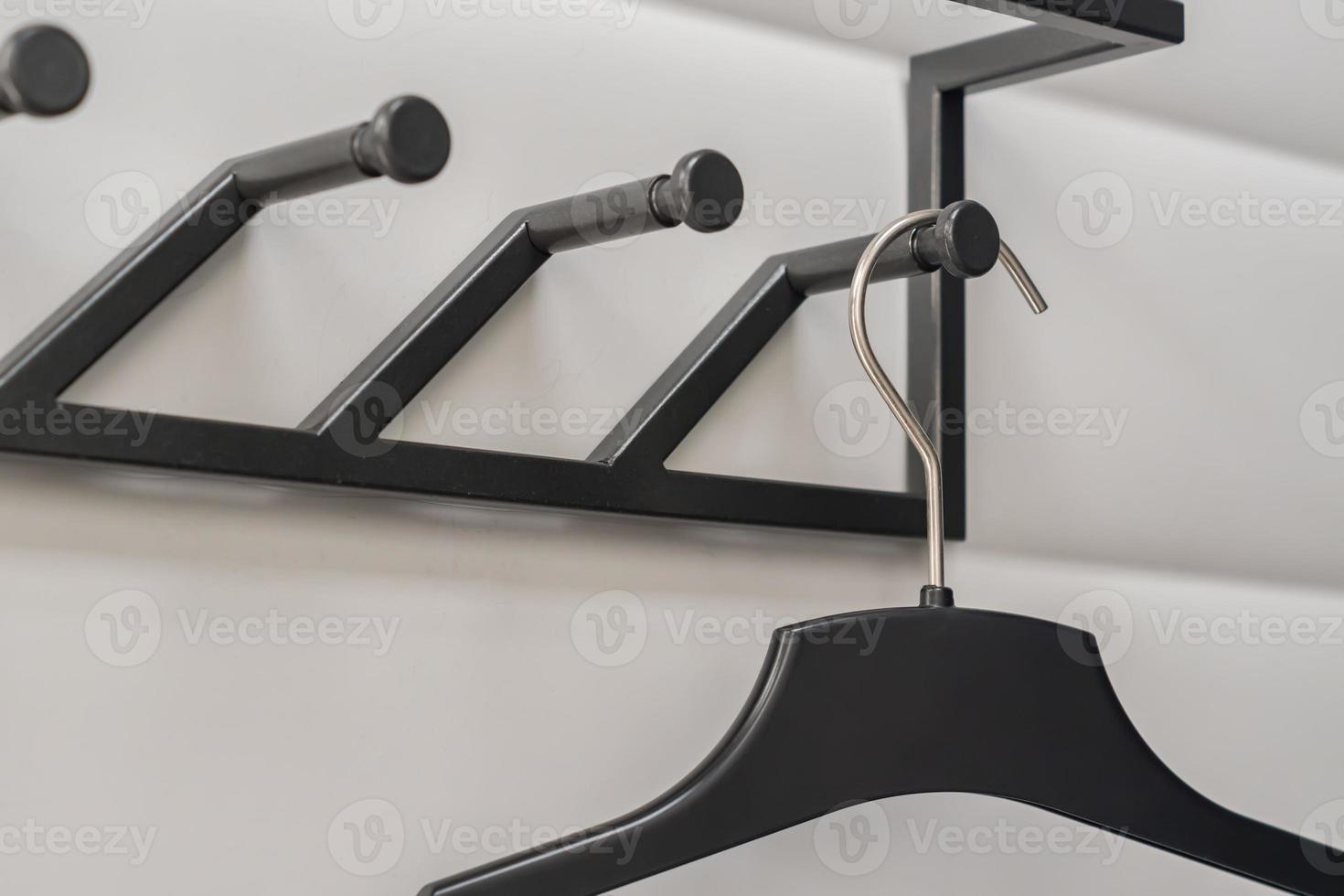 black plastic hangers on white wall background photo