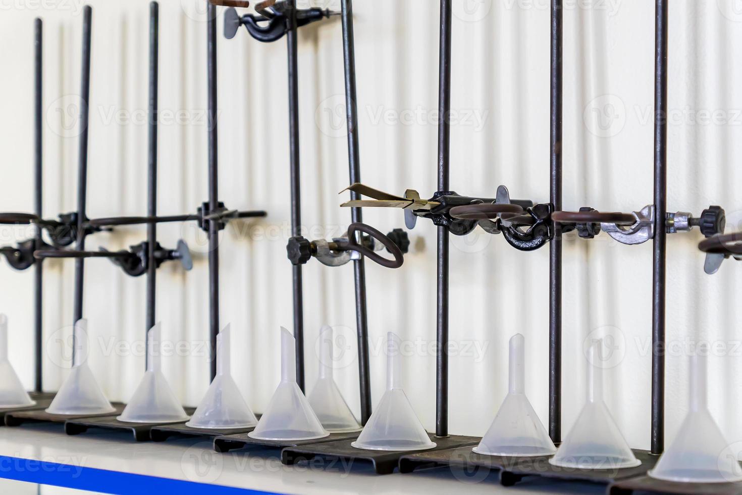 Laboratory equipment in a row - test tube holder, Clamps, plastic fiunnels photo