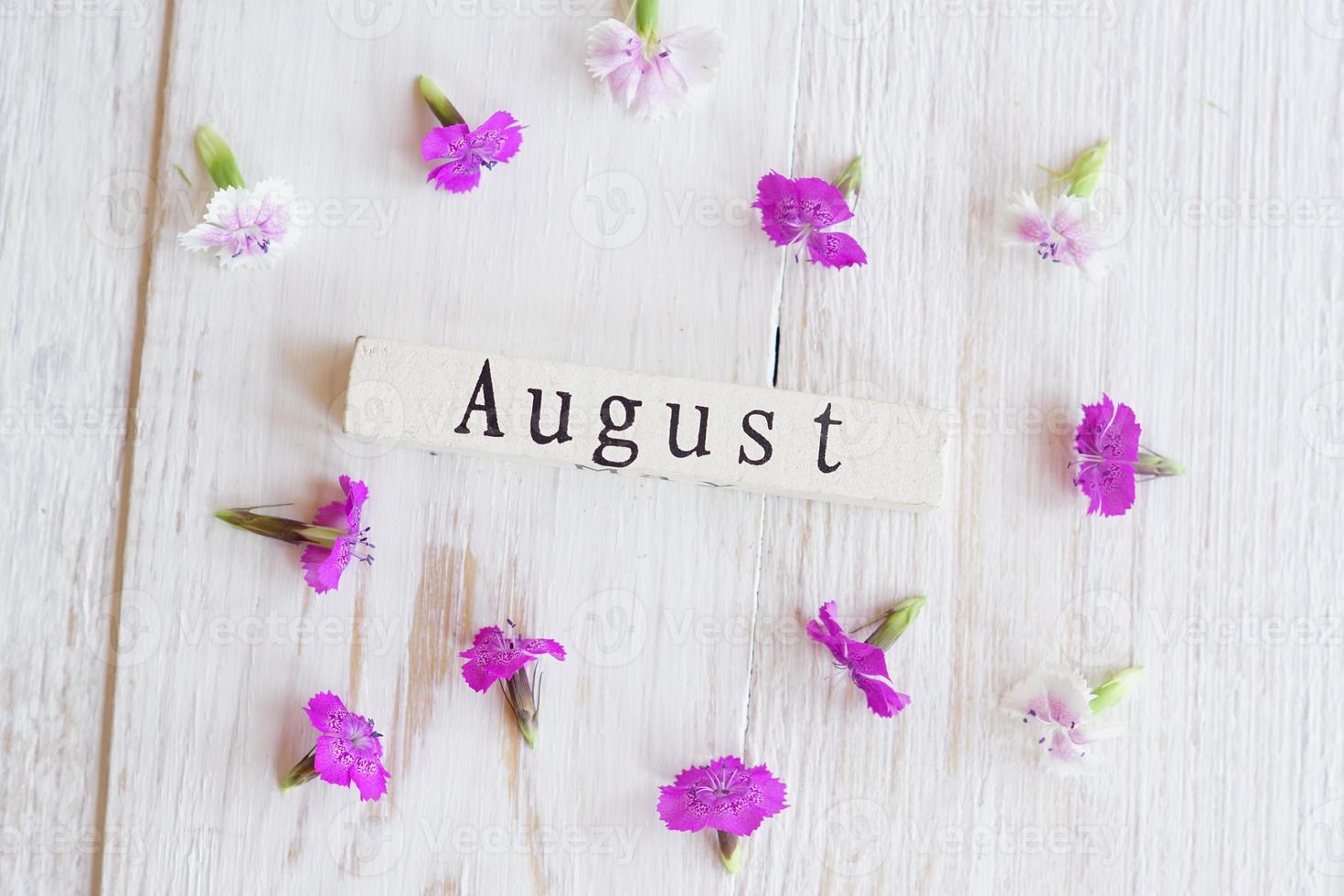 top view of wooden calendar with July sighn and pink flowers. photo