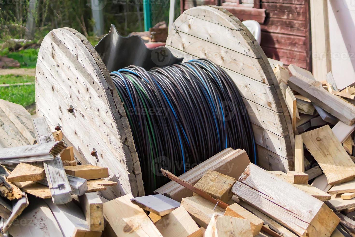 Wooden coil of electric cable among wooden logs in courtyard photo