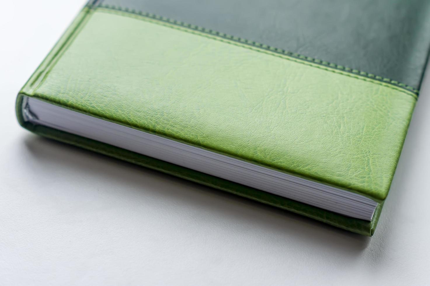 green business note book lying on the white table photo