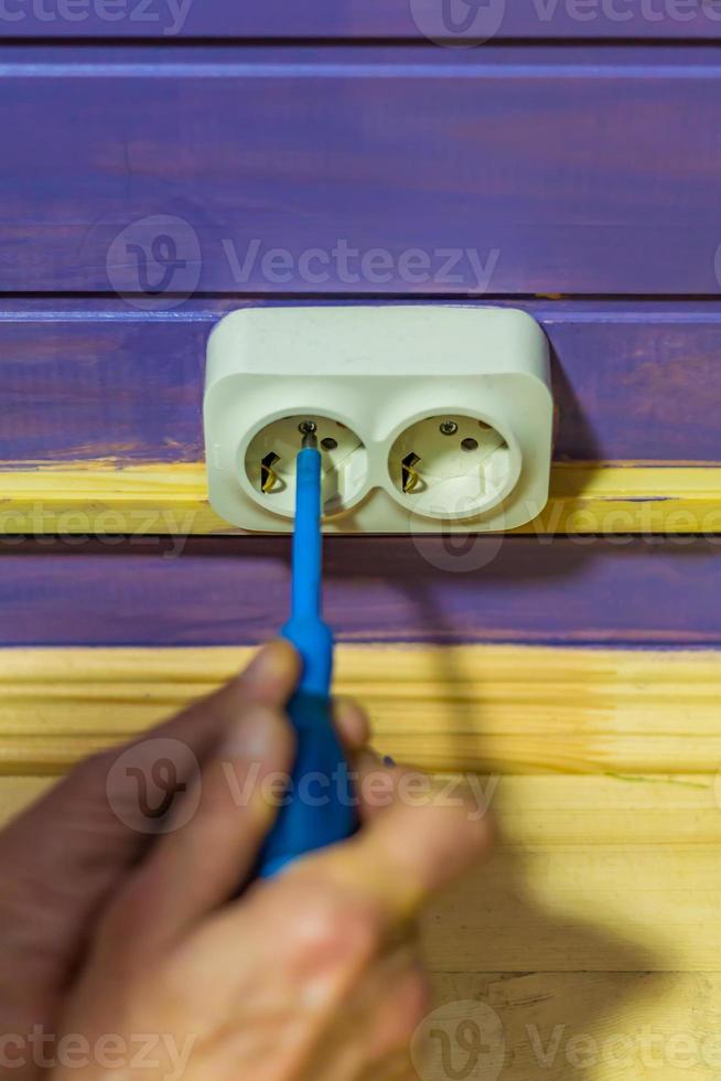 Closeup of man's hand installing socket on wooden wall at country house photo