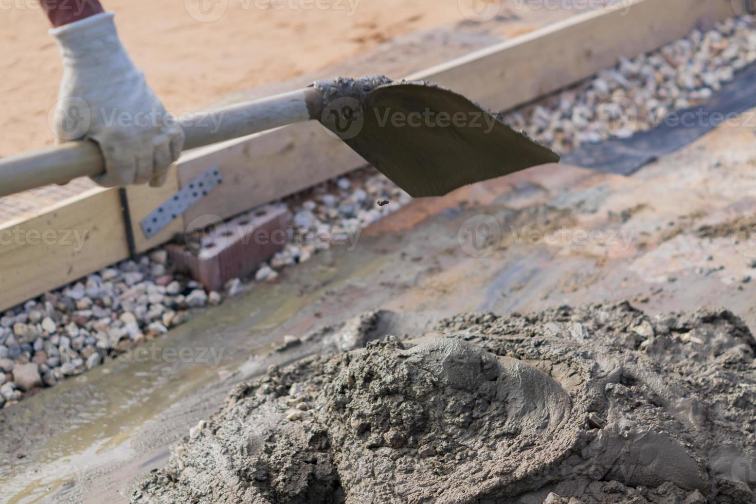 worker mixing concrete and gravel with spade on construction cite photo