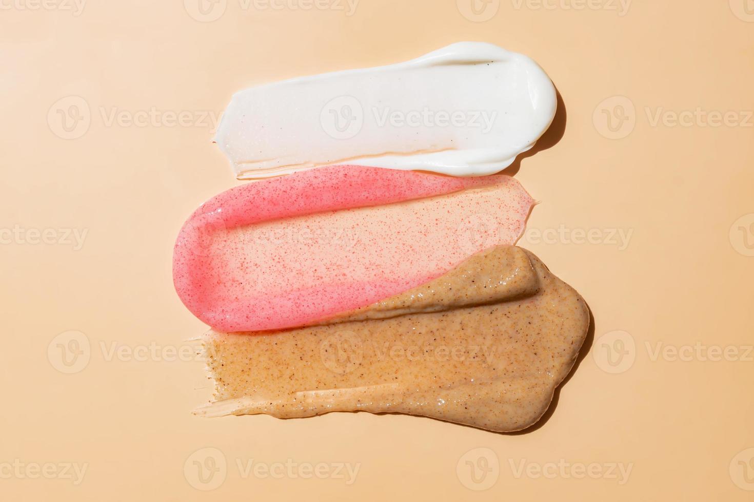 three types of face scrub on beige background. Face body skin peeling sample. Coffee, strawberry and creamy scrub. photo