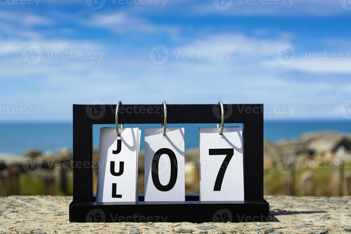 Jul 07 calendar date text on wooden frame with blurred background of ocean. photo