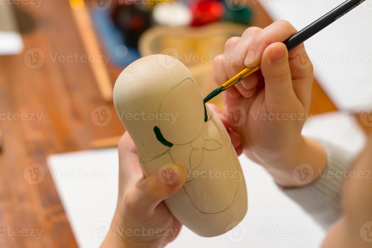 little girl paint russian nesting doll called matrioshka with green paint photo