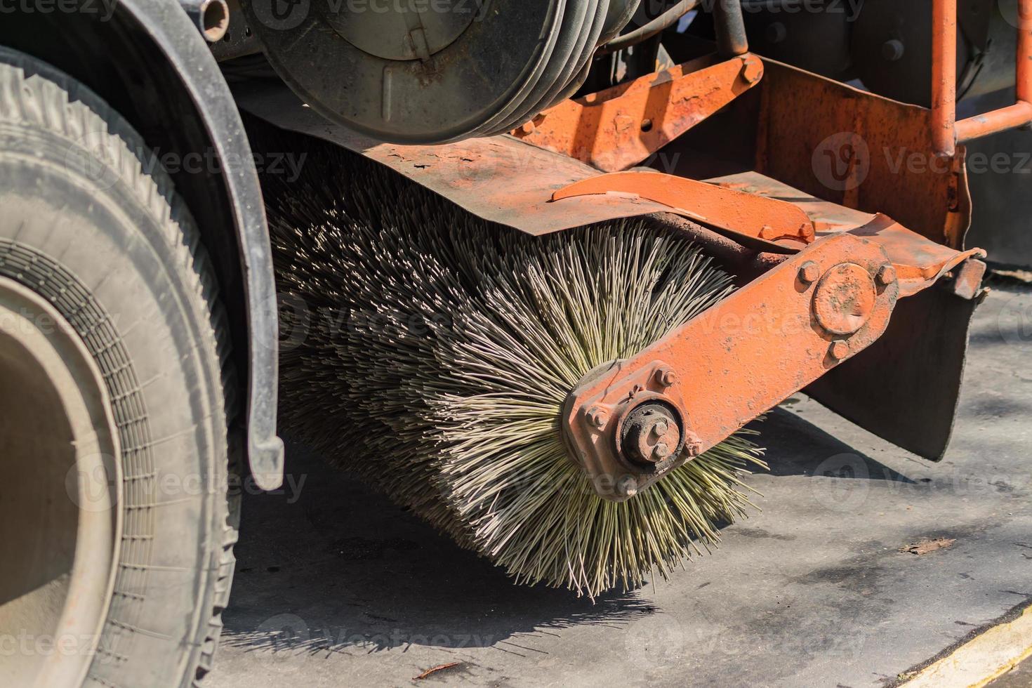 close up of street cleaning sweeper machine washes the asphalt road photo