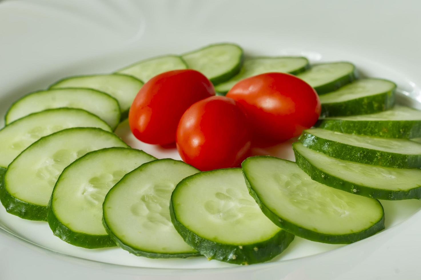cucumbers and cherry tomatoes on a white plate photo
