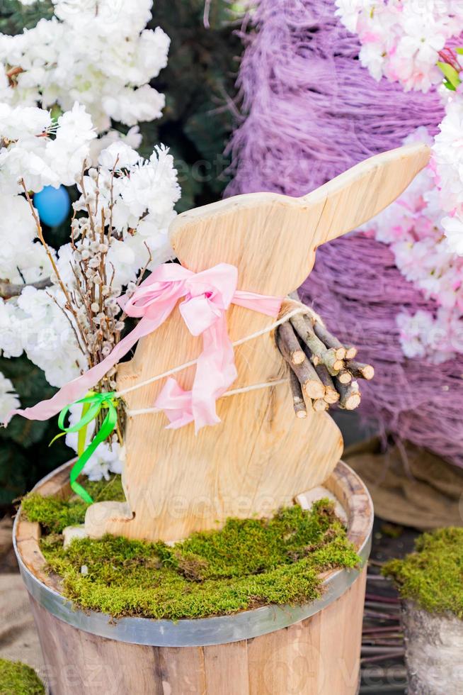 easter wooden bunny sitting in a moss on wooden barrel as decoration, outdoors photo
