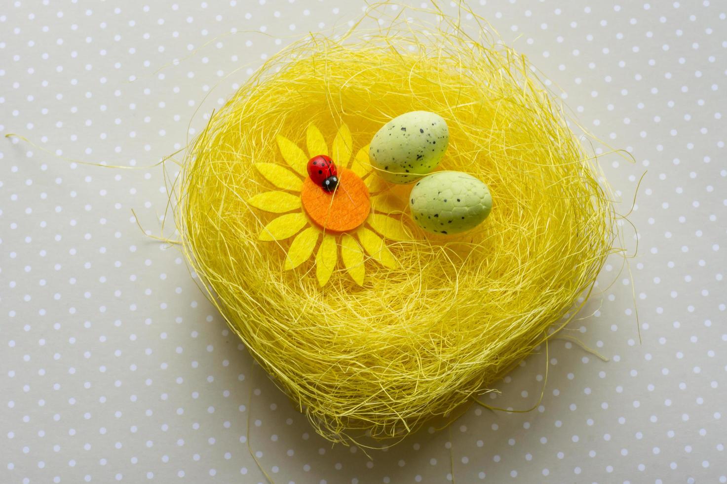 Artificial easter nest with two eggs, flower and ladybug photo