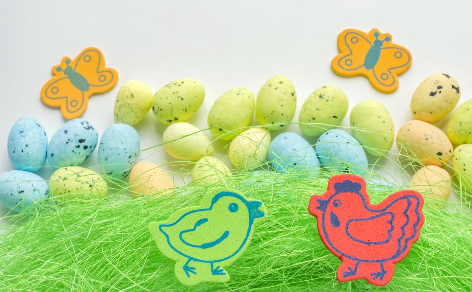 Artificial grass with colored eggs and two chickens background photo