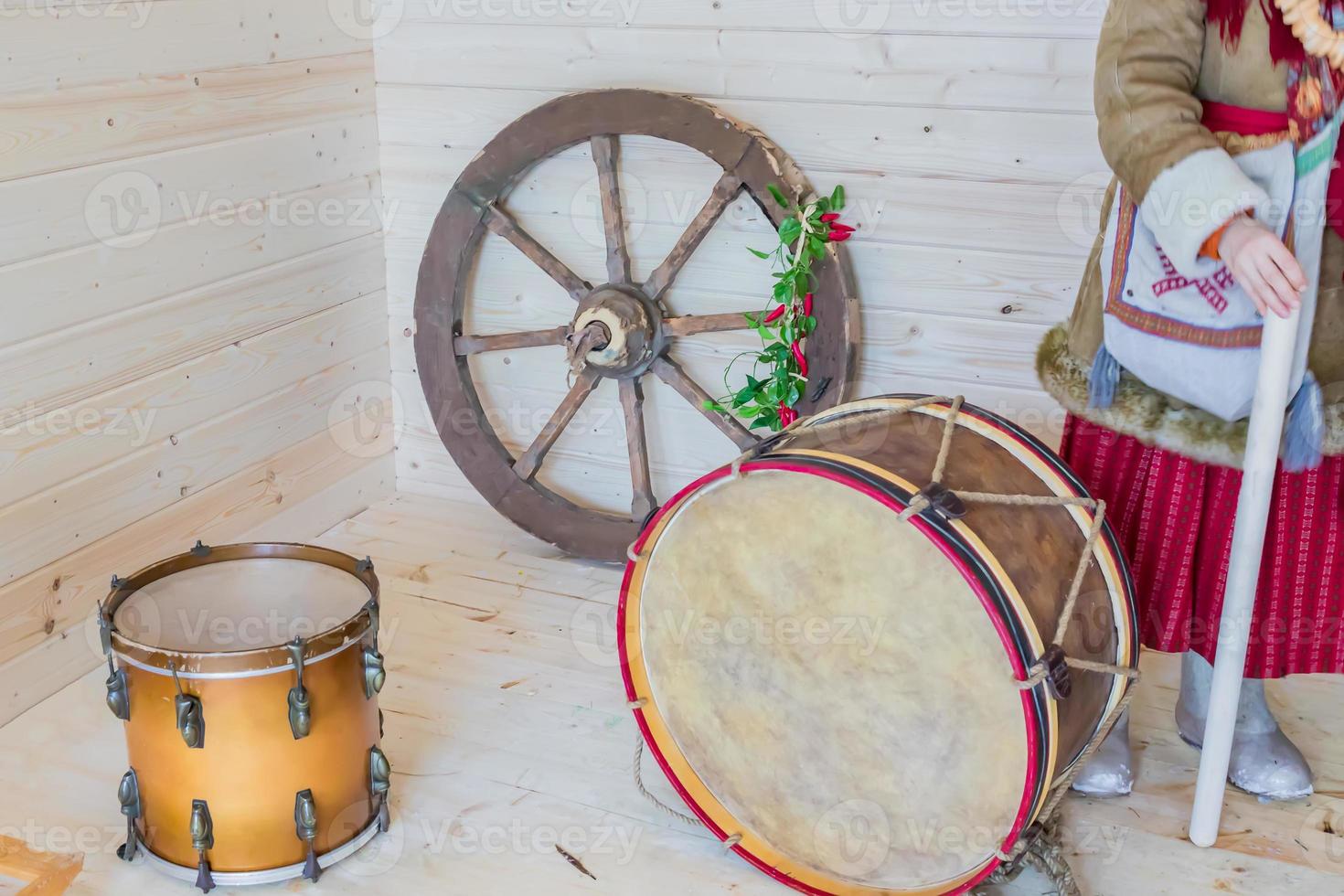 woman in traditional russian warm clothes in room with drums and stir wheel photo