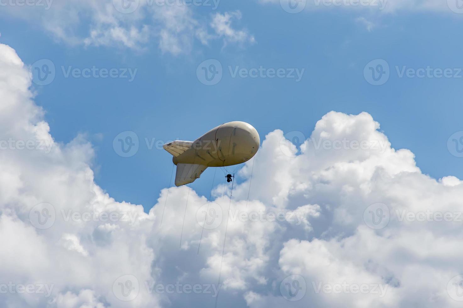 White airship of a soft system with stabilizers and a motor hovers in the sky photo