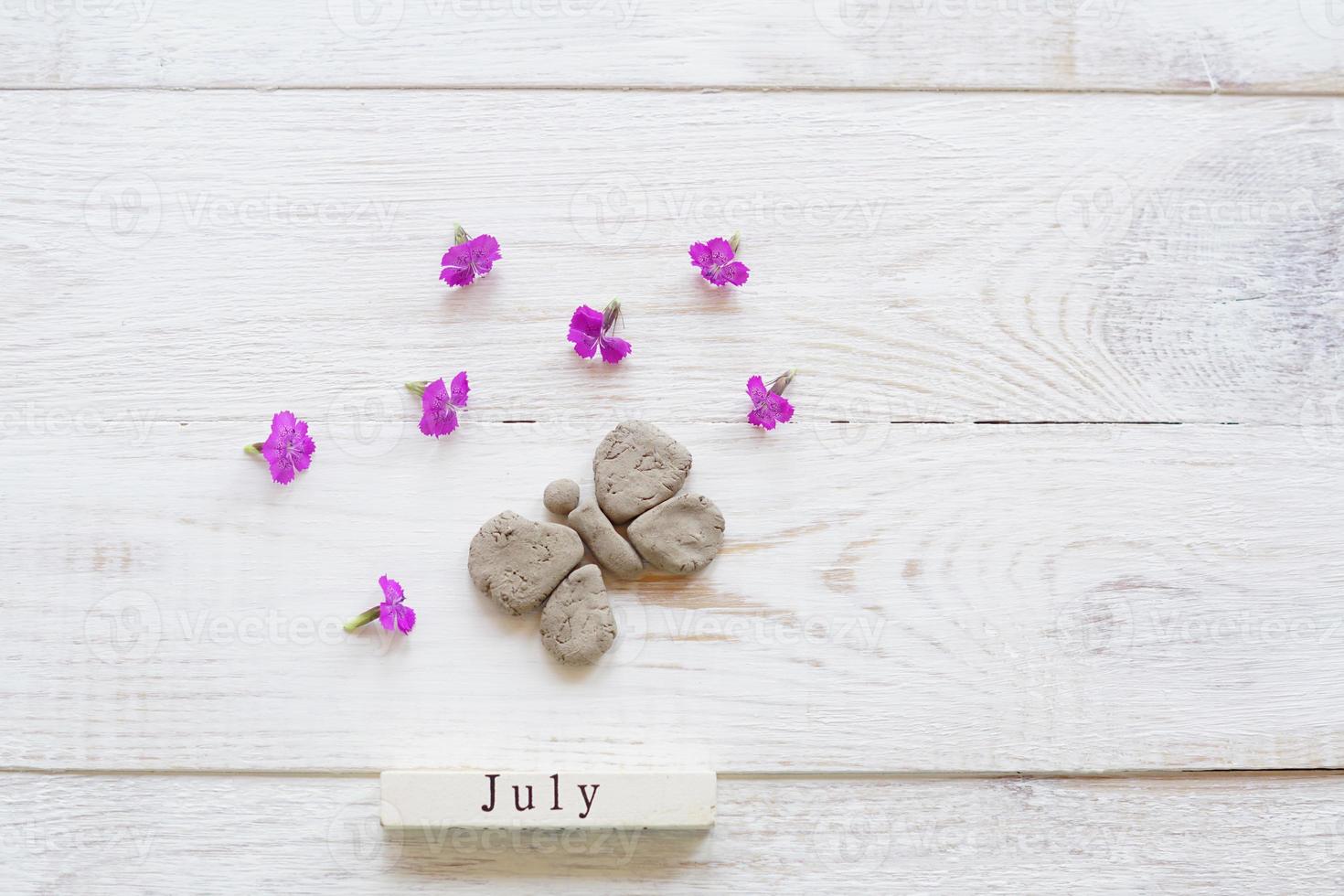 primer día de julio, fondo colorido con calendario, flores y mariposas de arcilla foto