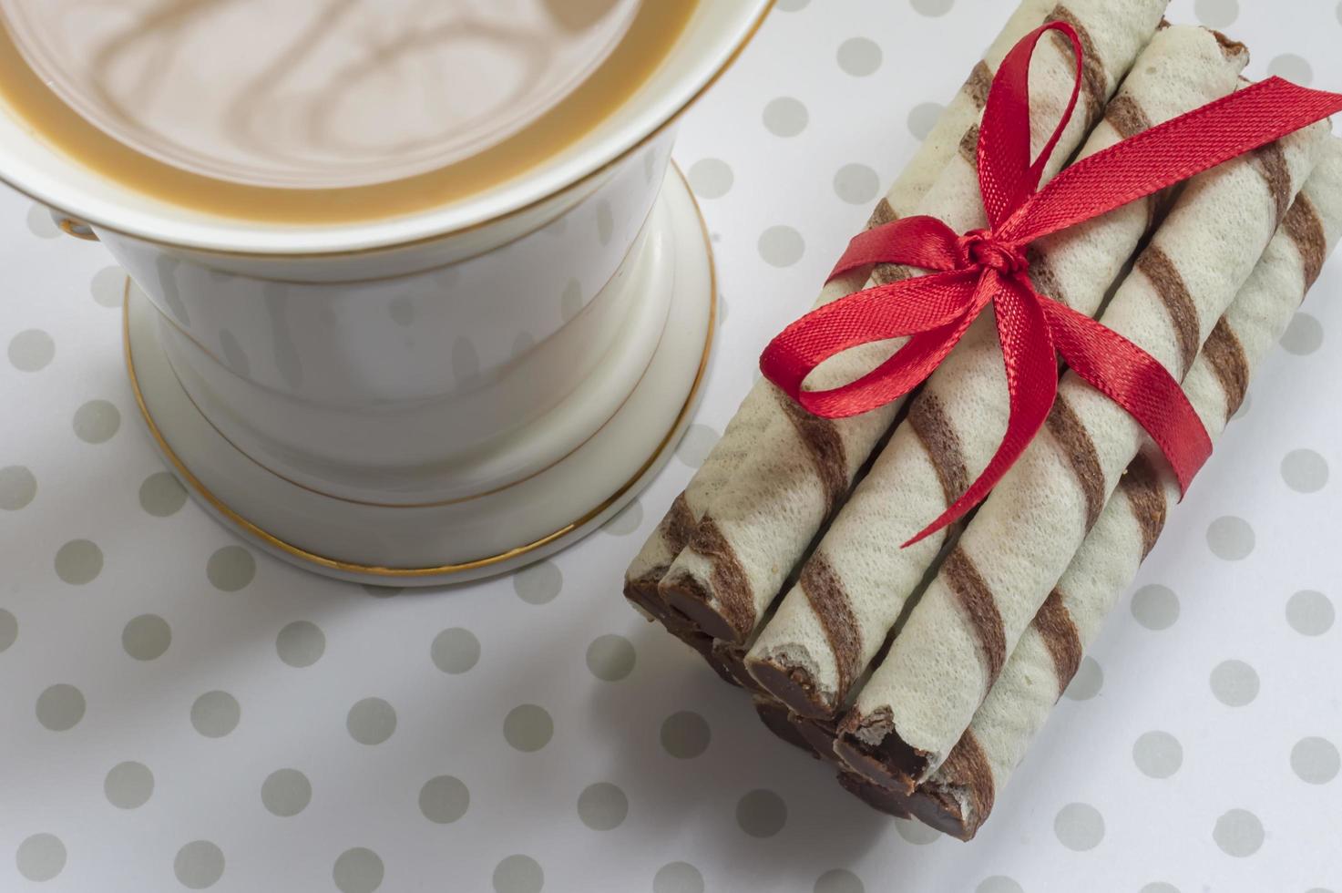 Wafer roll with chocolate and cocoa coating and cup of coffee with milk photo