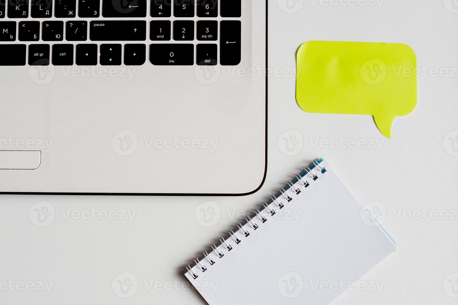 Closeup of white office desk with laptop, yellow sticker for notes and note book . Top view with copy space. photo
