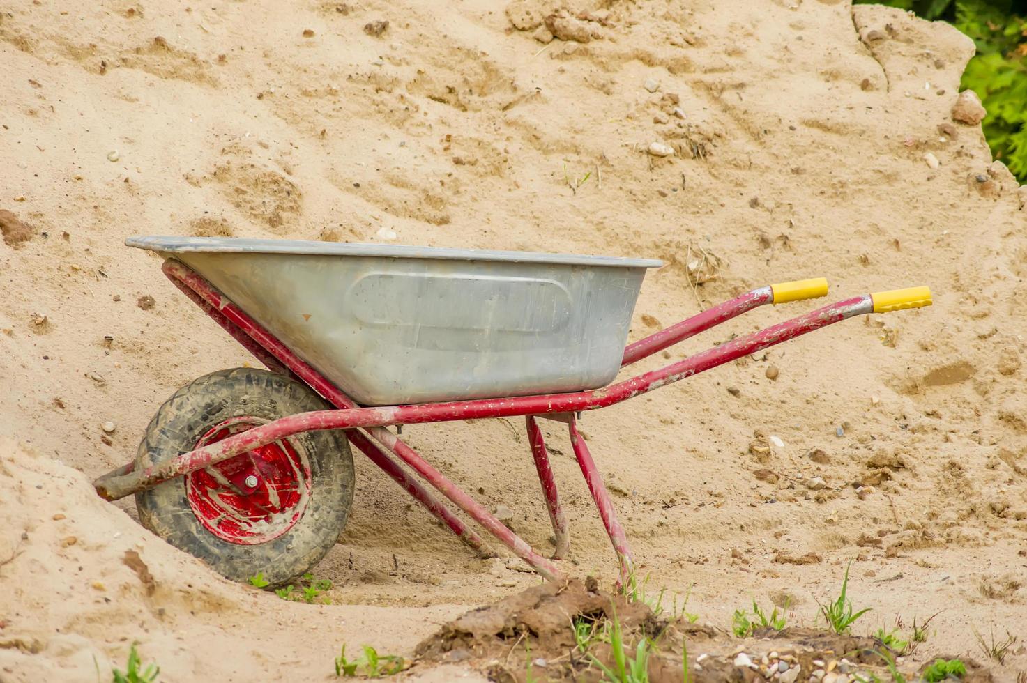 dirty wheelbarrow near pile of sand photo