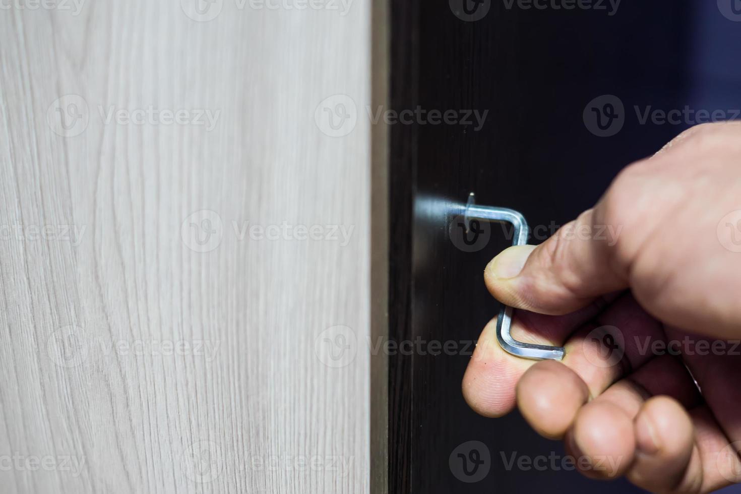 Assembling of furniture, closeup hex wrench in man hand photo