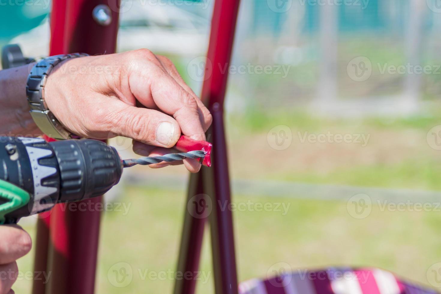 worker makes a hole in the metal with a drill photo