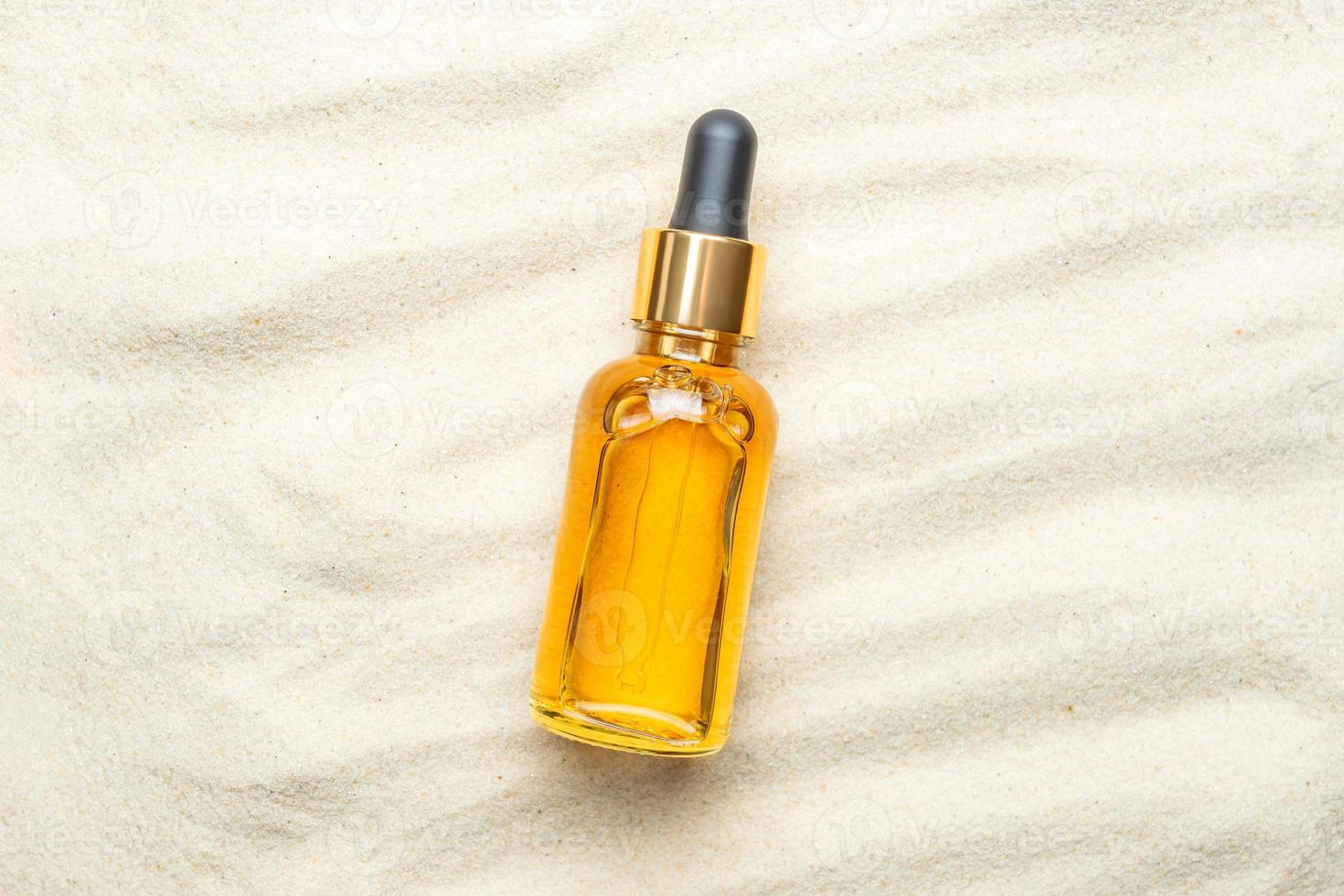Skincare with beauty cosmetic face serum. Glass bottle with a pipette on a natural sandy background. Essential oil or Vitamin C cerum for moisturizing body skin. Copy space photo