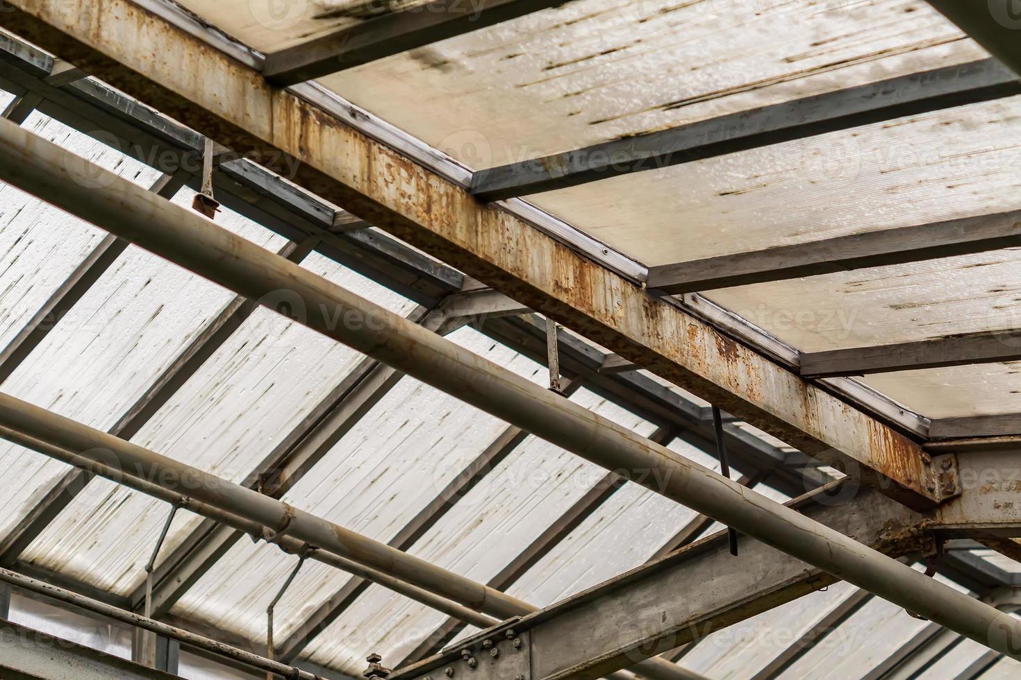 metal and glass roof of a greenhouse with pipes photo