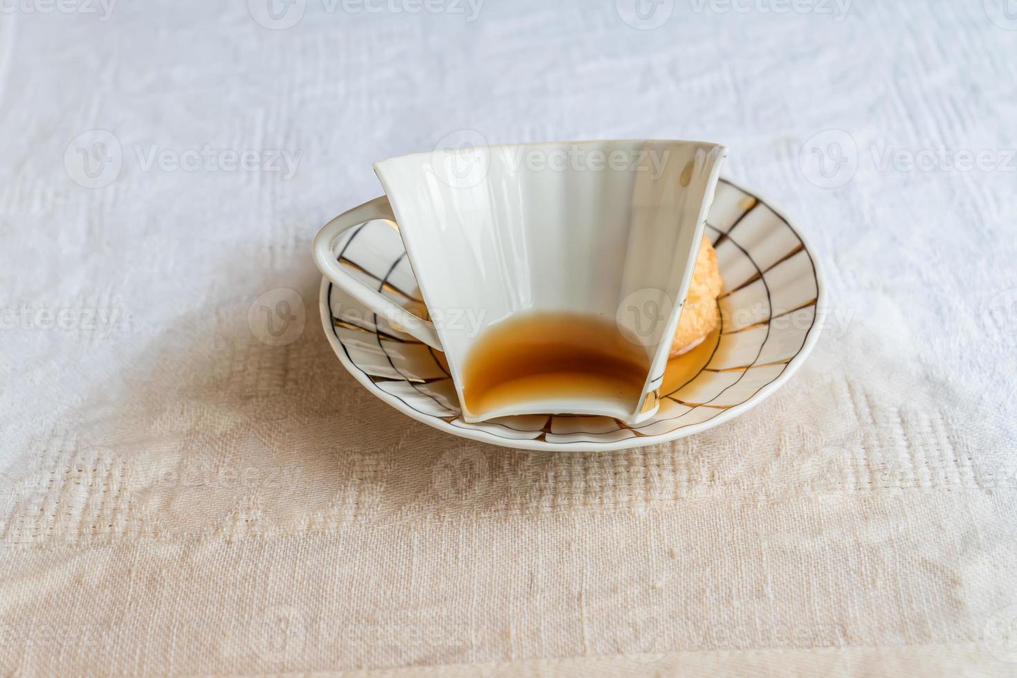 broken porcelain cup with tea and cookie on cotton tablecloth photo