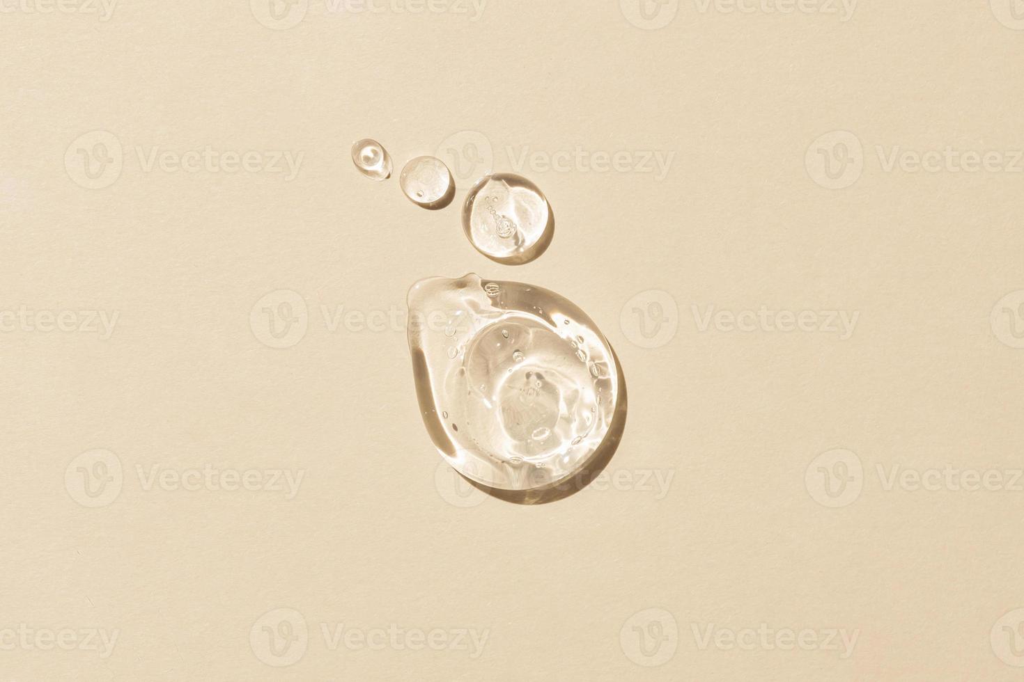 Glycerin gel texture. Transparent serum drop on beige background. Liquid gel moisturizer with bubbles macro photo