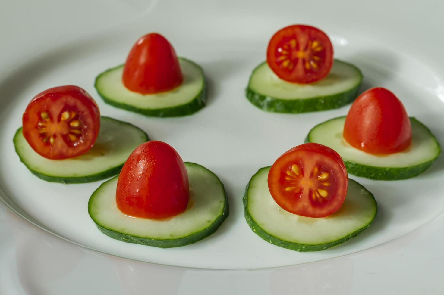 cucumbers and cherry tomatoes on a white plate photo