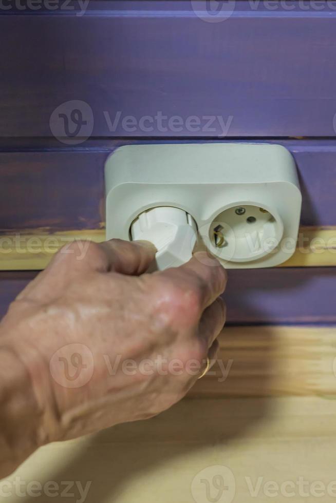 hand unplugging a plug from a socket photo
