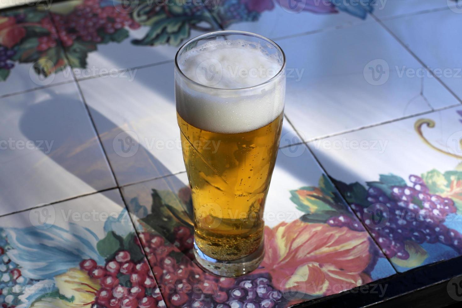 On the table in a glass of fresh and cold beer. photo