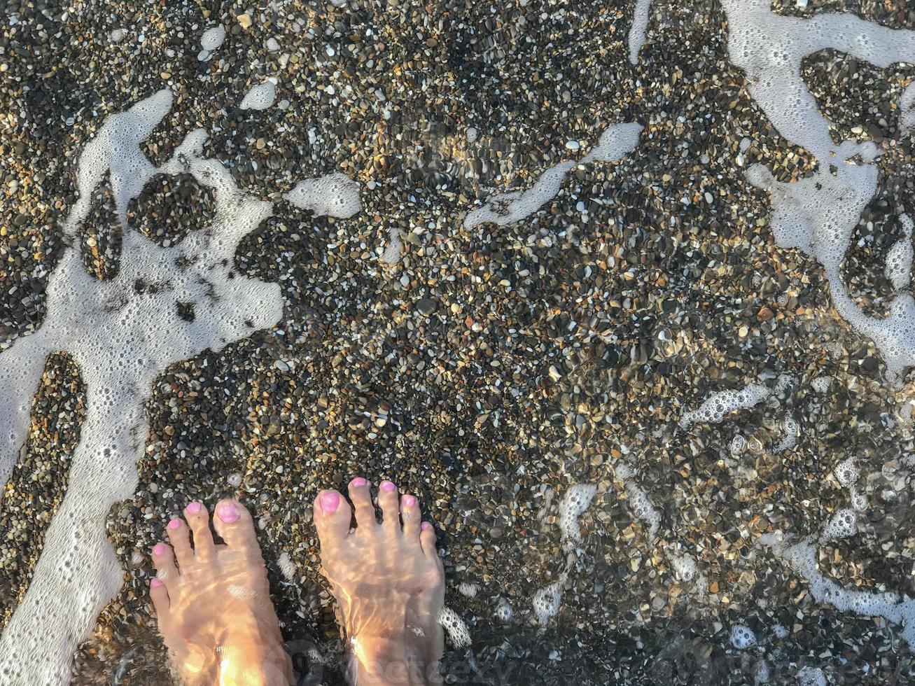 a pair of woman's feet on pebble beach background photo