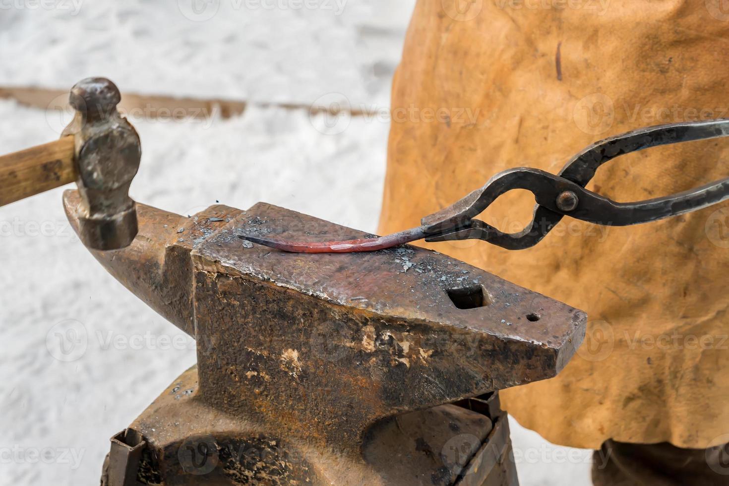 blacksmith manually forging the molten metal on the anvil outdoors photo