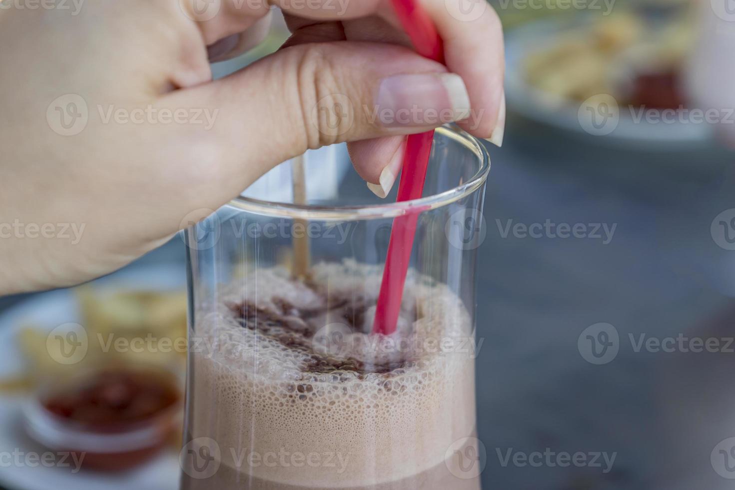 Cóctel de batido de chocolate en mano de mujer en la terraza abierta horario de verano foto